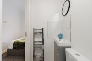 Uma casa de banho com uma pia branca, um espelho e um porta-toalhas.