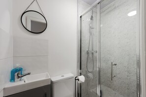 A bathroom with a glass-enclosed shower, a sink with a faucet, a toilet, a mirror, and a bottle of hand soap. - 4 bed, 4 en-suite house (Warrington)
