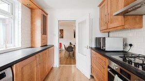 A modern kitchen with wooden cabinets, a gas stove, and a dining area visible through an open door. - 4 bed, 4 en-suite house (Warrington)