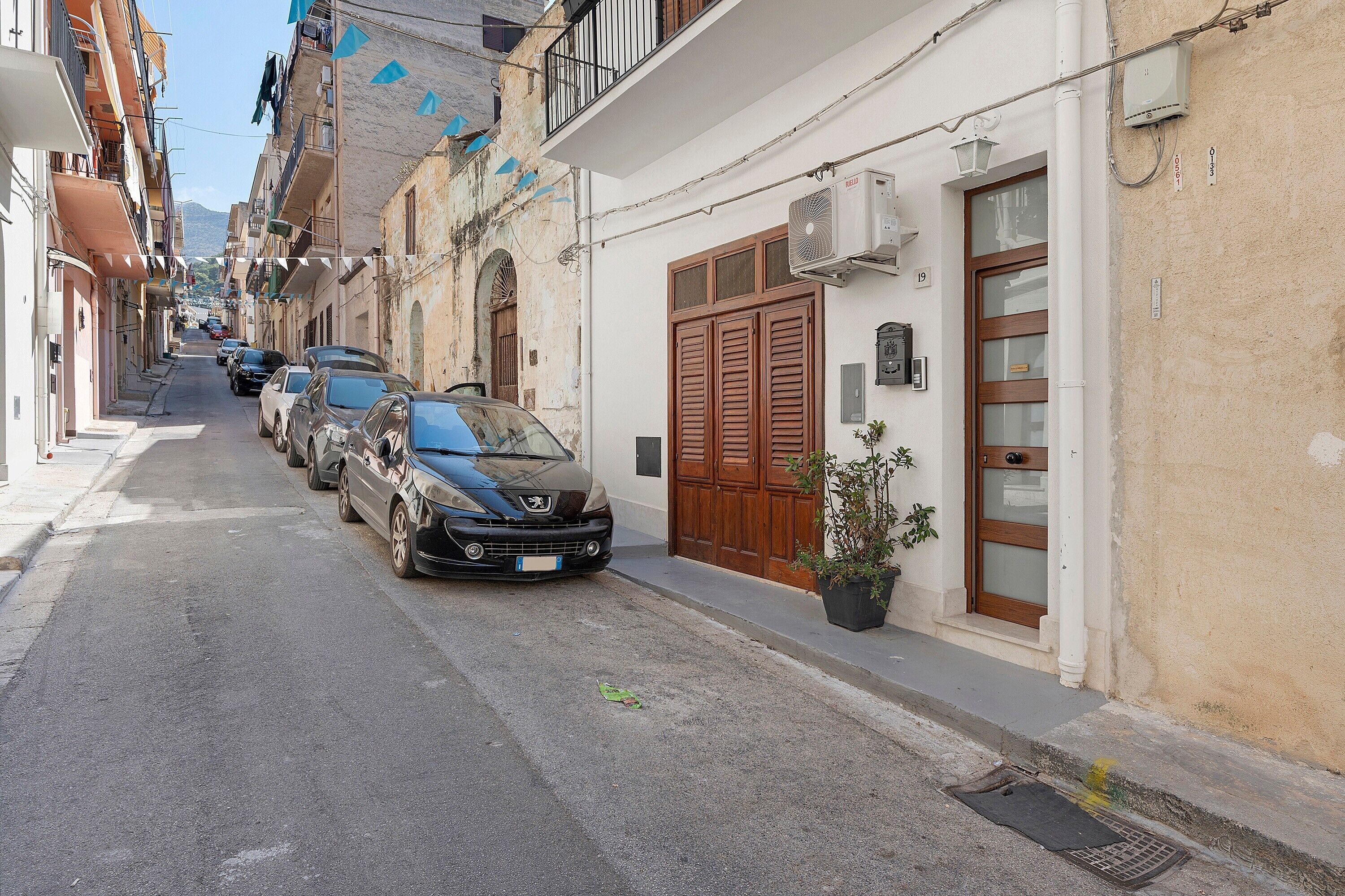 Una calle estrecha bordeada de coches estacionados y edificios con balcones.