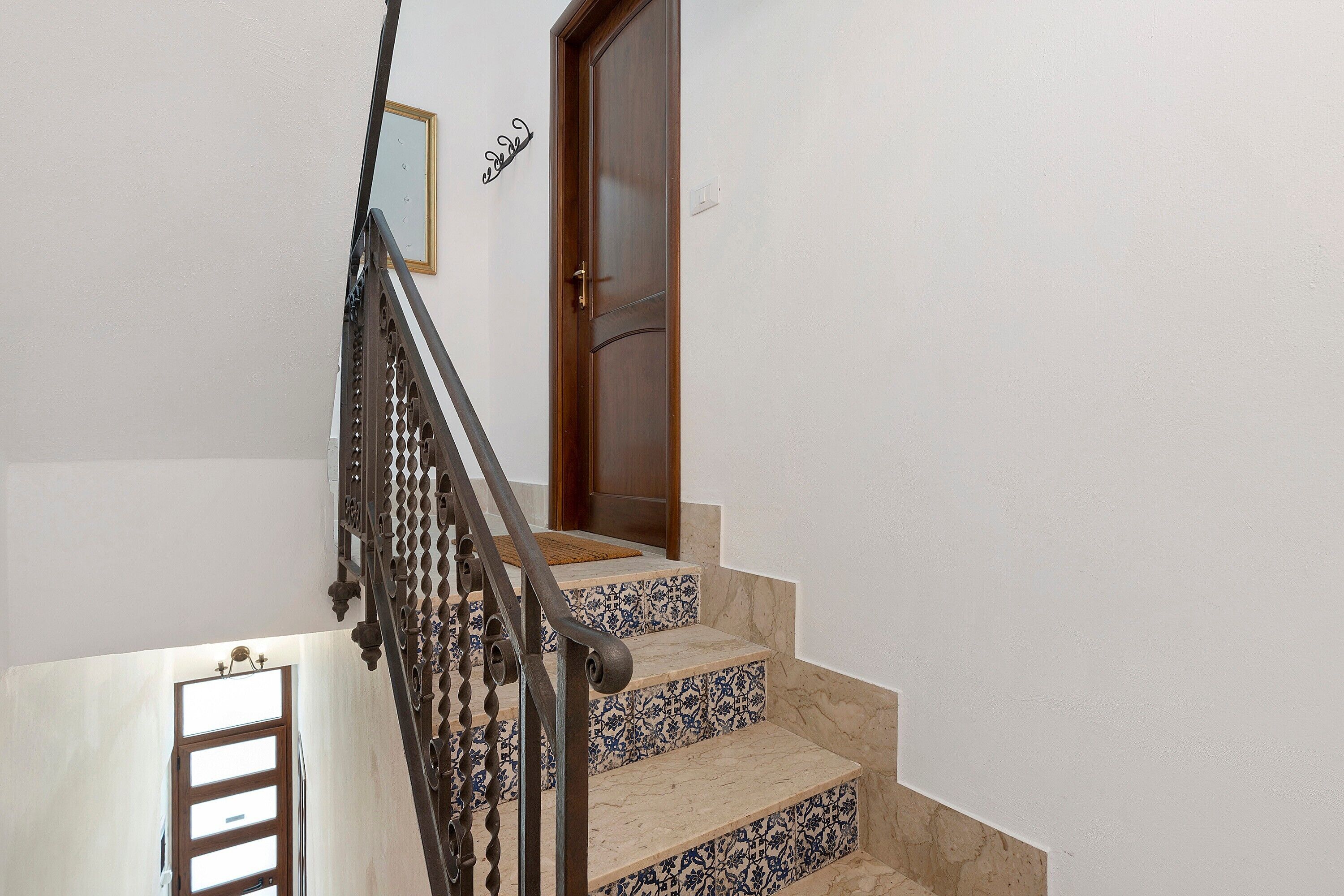 Una escalera con barandilla metálica y una puerta de madera al final.