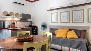 A compact living space with a kitchenette, dining area, and a bed with a striped headboard. - Apartment 'Appartamento Romeo' with Balcony, Wi-Fi and Air Conditioning (Castellammare del Golfo)