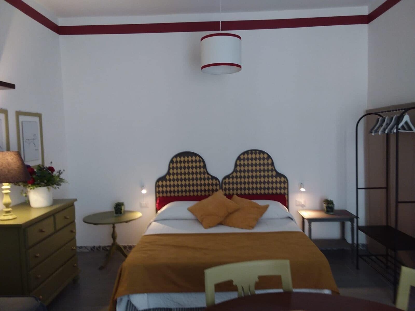 Ein Schlafzimmer mit einem Bett, einem Nachttisch, einer Lampe, einer Kommode und einem Sessel.
