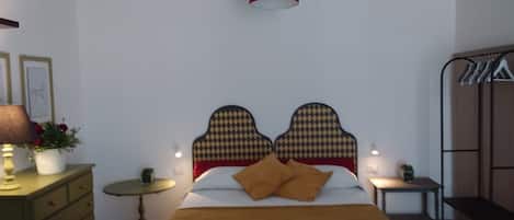 A bedroom with a bed, a bedside table, a lamp, a dresser, and a chair.