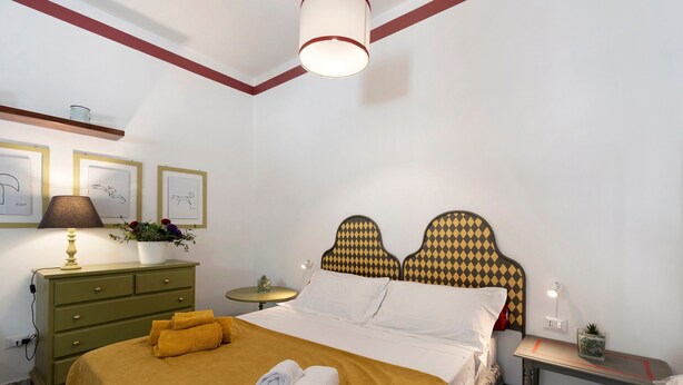 A hotel room with a bed, a bedside table, a lamp, a dresser, and framed artwork on the wall. - Apartment 'Appartamento Romeo' with Balcony, Wi-Fi and Air Conditioning (Castellammare del Golfo)