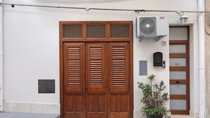 Fachada de edificio con una puerta doble de madera, una pequeña planta en maceta y un buzón.