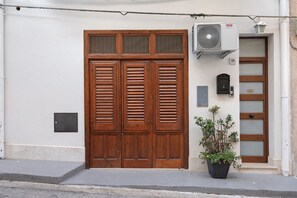 Une façade d’immeuble avec une grande porte à double battant en bois, une petite plante en pot et une fente pour le courrier.