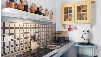 Eine Küche mit modernem Herd, einer Kaffeemaschine und einem Schrank mit Glastüren.