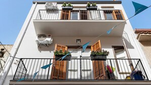 Un edificio de dos pisos con balcones, unidades de aire acondicionado y jardineras de flores.