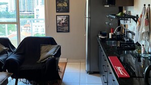 Una cocina moderna con refrigerador, lavaplatos y un área de comedor con sofá y mesa.