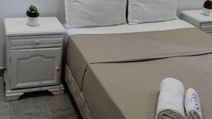 Et hotelværelse med en seng, et natbord, en lille stueplante og et pænt foldet håndklæde.