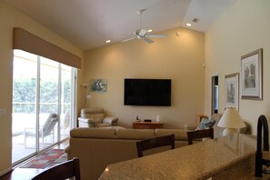 Ein Wohnzimmer mit Flachbildfernseher, Deckenventilator und Essbereich mit Granitplatte.