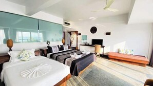 Ein modernes Hotelzimmer mit zwei Betten, einer Couch, einem Fernseher und einem Deckenventilator.