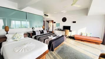 A modern hotel room with two beds, a sofa, a TV, and a ceiling fan.