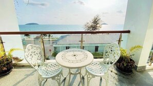 Ein Balkon mit Tisch und Stühlen, der auf ein Gewässer und eine ferne Insel blickt.