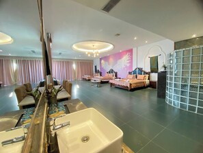 Un hall de hotel con mostrador de recepción, zona de estar y un espejo grande.