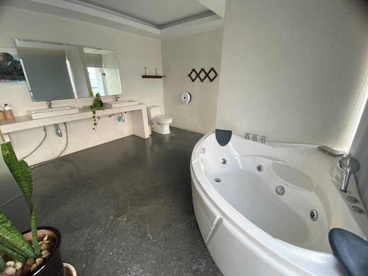 A modern bathroom with a large bathtub, a double sink vanity, and a toilet.