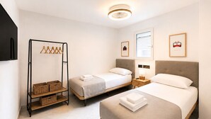 Habitación de hotel con dos camas, un armario, un televisor y una lámpara en el techo.