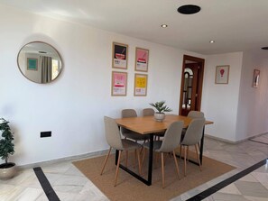 A dining area with a wooden table and six chairs, a potted plant, and a mirror on the wall. - Torremolinos Collection Apartments (Torremolinos)