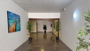 Un pasillo con piso pulido, paredes de ladrillo blanco y plantas en macetas.