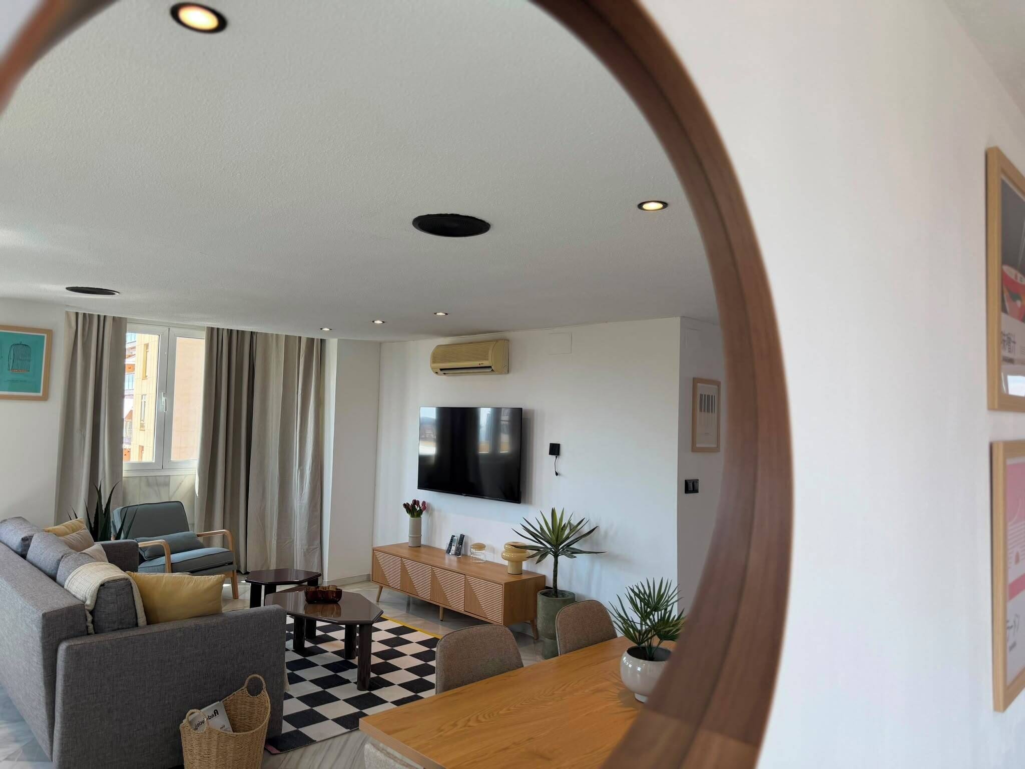 Ein modernes Wohnzimmer mit einer Couch, einem Couchtisch, einem an der Wand befestigten Fernseher und einem Schachbrettmuster-Boden.