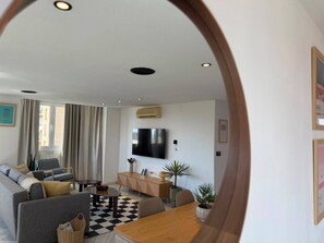 A modern living room with a sofa, a coffee table, a TV mounted on the wall, and a checkered floor. - Torremolinos Collection Apartments (Torremolinos)