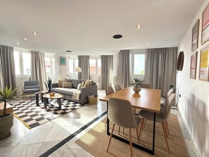 Ein modernes Wohnzimmer mit Sofa, Esstisch, Stühlen und einem Schachbrettmuster-Boden.