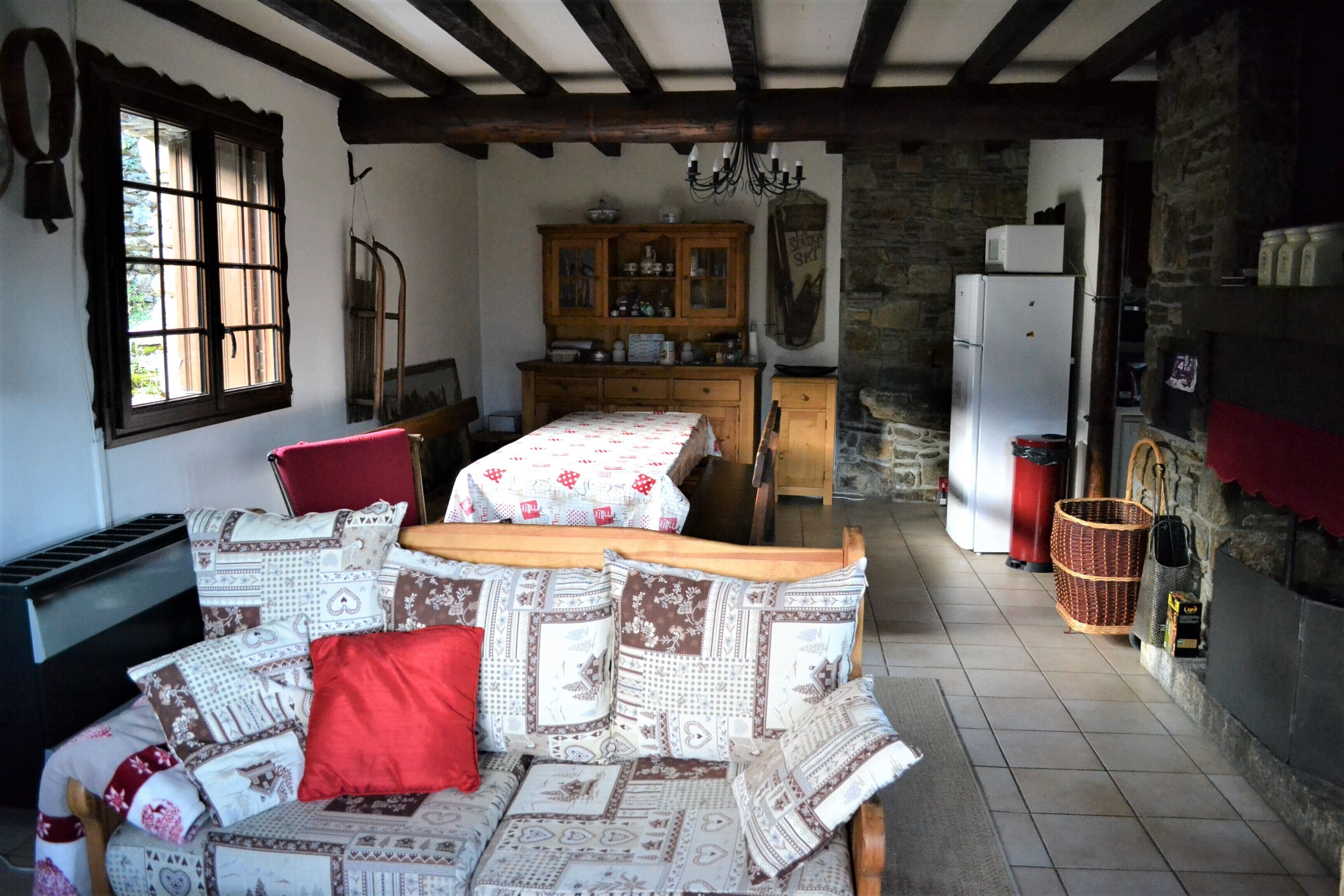 A cozy room with a sofa, a dining table, and a kitchen area with a refrigerator and cabinets.