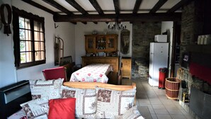 A cozy room with a sofa, a dining table, and a kitchen area with a refrigerator and cabinets.