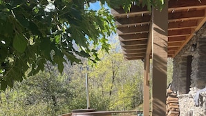 An outdoor patio with stone flooring, a wooden table set for dining, and a hot tub.