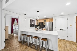Une cuisine moderne dotée d’un îlot central, de tabourets de bar et offrant une vue sur l’extérieur.