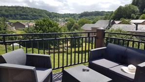 Un balcone con mobili da esterno, vista su un paesaggio verde e cielo sereno.
