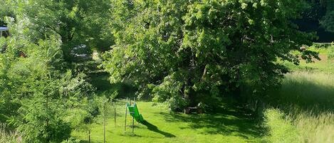 A grassy area with trees and a playground structure.