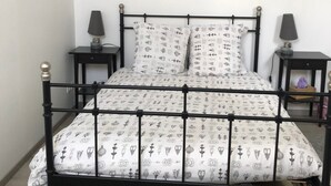 A bed with a patterned bedspread, two bedside tables with lamps, and a wall-mounted artwork.