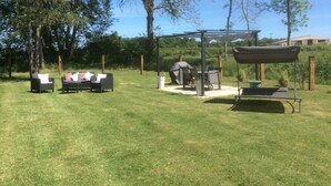 An outdoor patio area with a pergola, a barbecue grill, and seating arrangements.