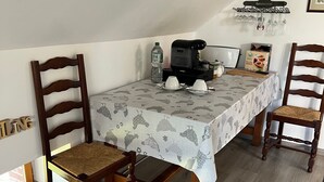 Ruokailutila, jossa on kahdelle katettu pöytä, kahvinkeitin ja vesipullo.