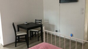 A room with a dining table, chairs, a television mounted on the wall, and a white railing.