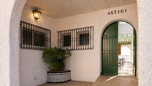 An arched entrance with a tiled floor, a potted plant, and a sign that reads 'ASTIGI'.
