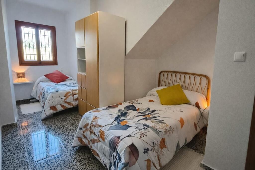Une chambre avec deux lits, une armoire, une fenêtre et un plafond en pente.