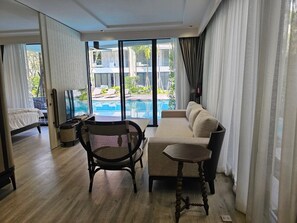 Una habitación amplia con un ventanal, un sofá, una silla y una mesita.