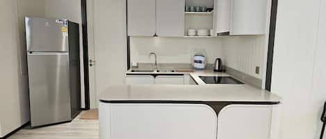 Una cocina moderna con una isla integrada, refrigerador de acero inoxidable y gabinetes blancos.