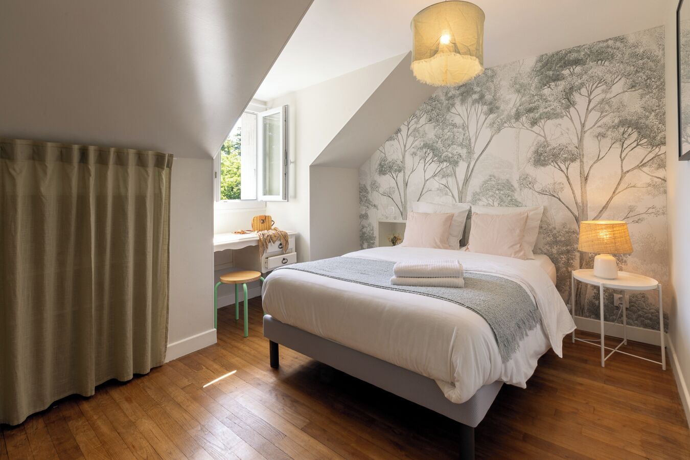 Quarto com cama, escrivaninha, cadeira, luminária e janela com cortinas.