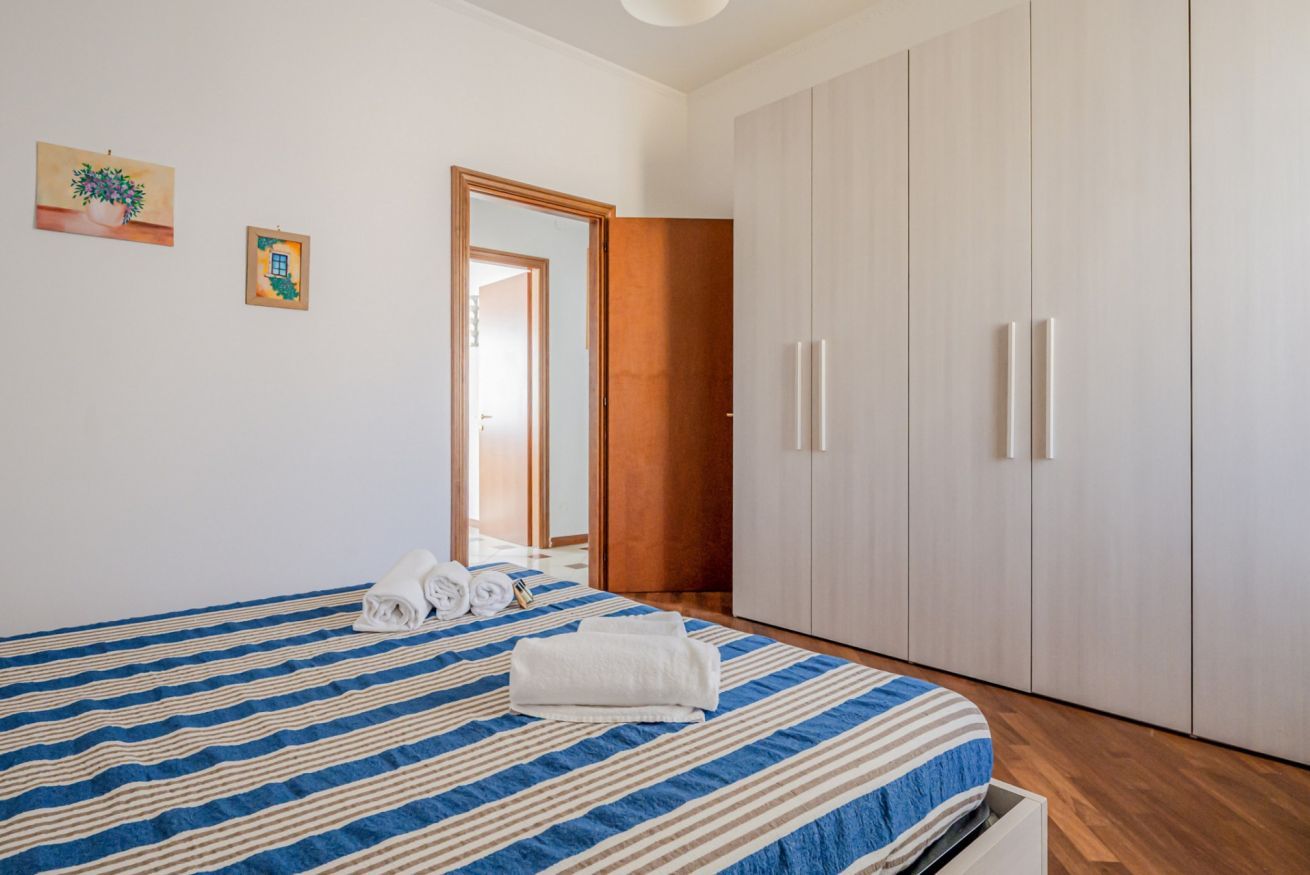 A bedroom with a bed, a wardrobe, and a door leading to another room.