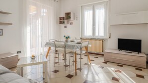 Moderni, hyvin valaistu huone, jossa on ruokapöytä, tuoleja, televisio ja patteri.