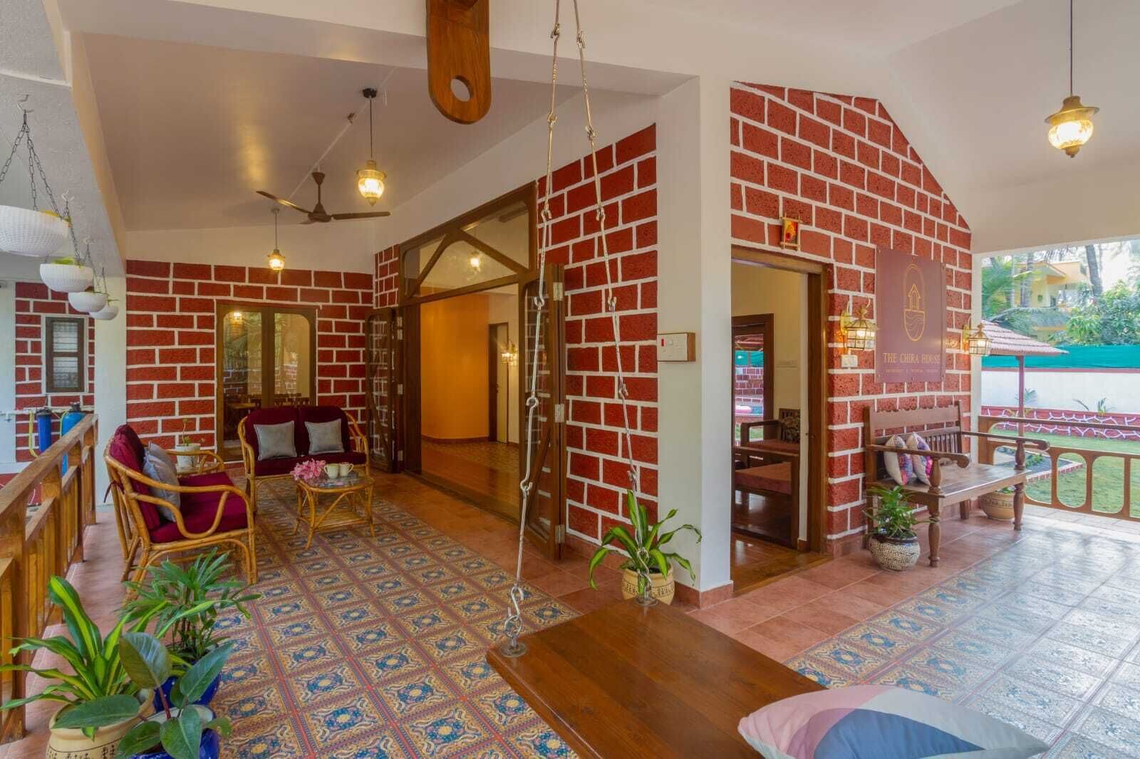 A room with a brick wall, a wooden bench, a sofa, and a hanging light fixture.