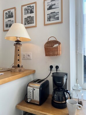 Eine Küchenzeile mit Toaster, Kaffeemaschine und einem Korb an der Wand.