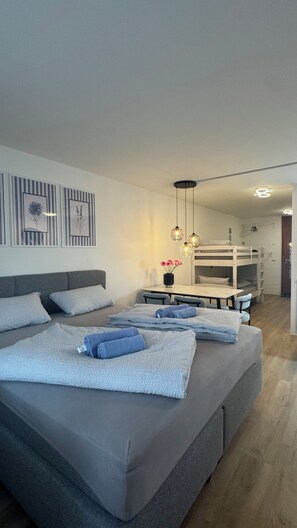 Een moderne slaapkamer met een stapelbed, een eettafel en een kleine keukenhoek.