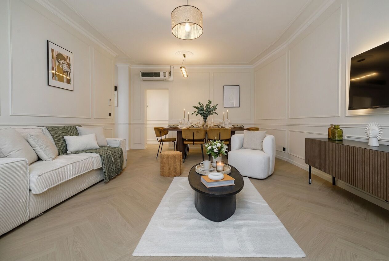 A modern living room with a sofa, a coffee table, and a dining area with chairs.