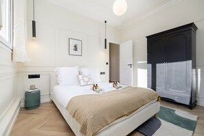 Een slaapkamer met een bed, nachtkastjes, een kledingkast en een lijst met een afbeelding aan de muur.