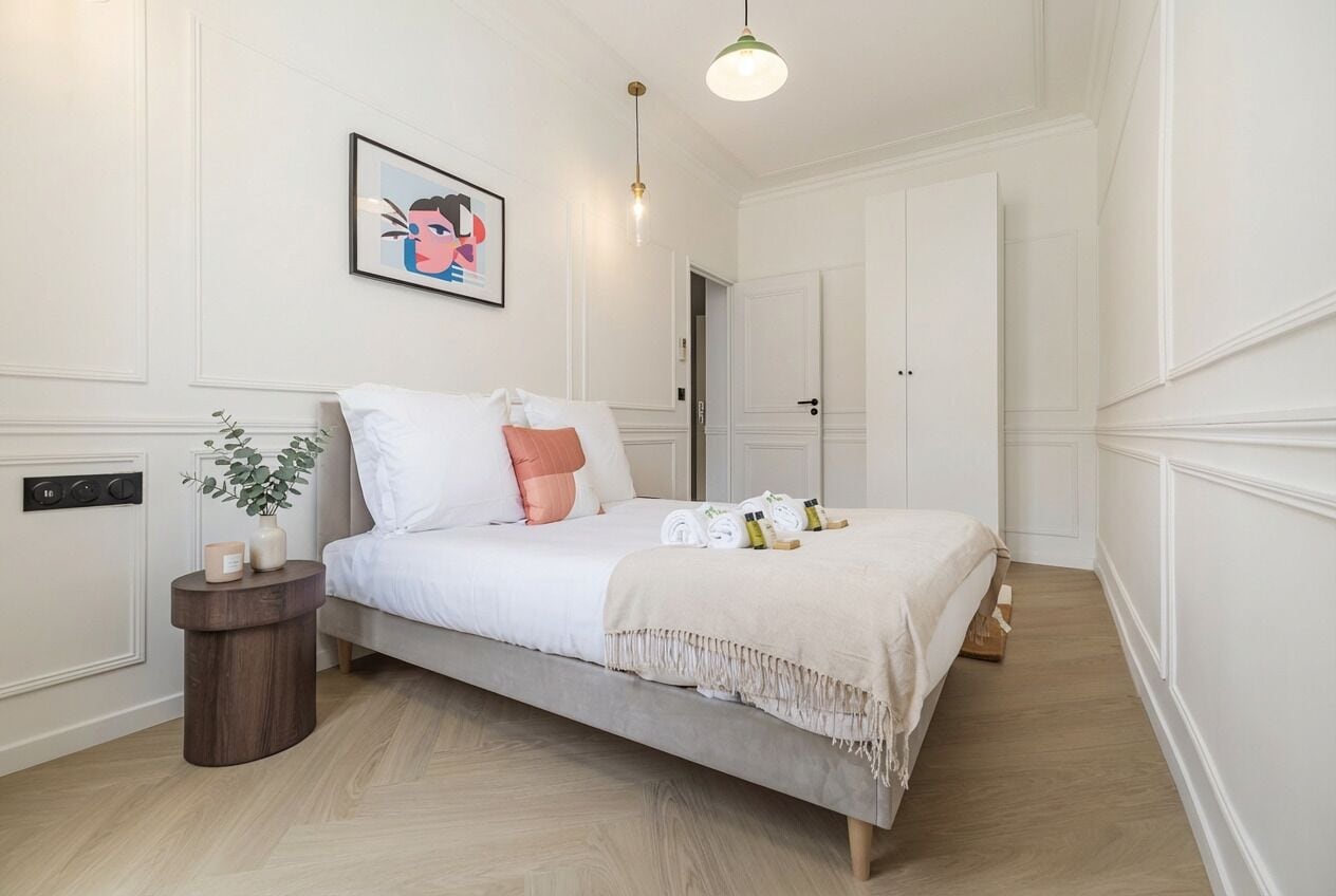 Une chambre à coucher avec un lit, une table de chevet et un tableau accroché au mur.